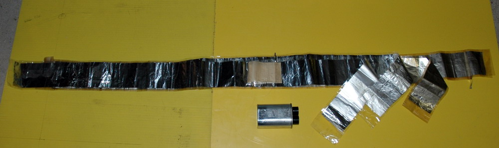 The specific capacitors for the Tesla coil are rewound from the existing capacitor in a messy, oily process.