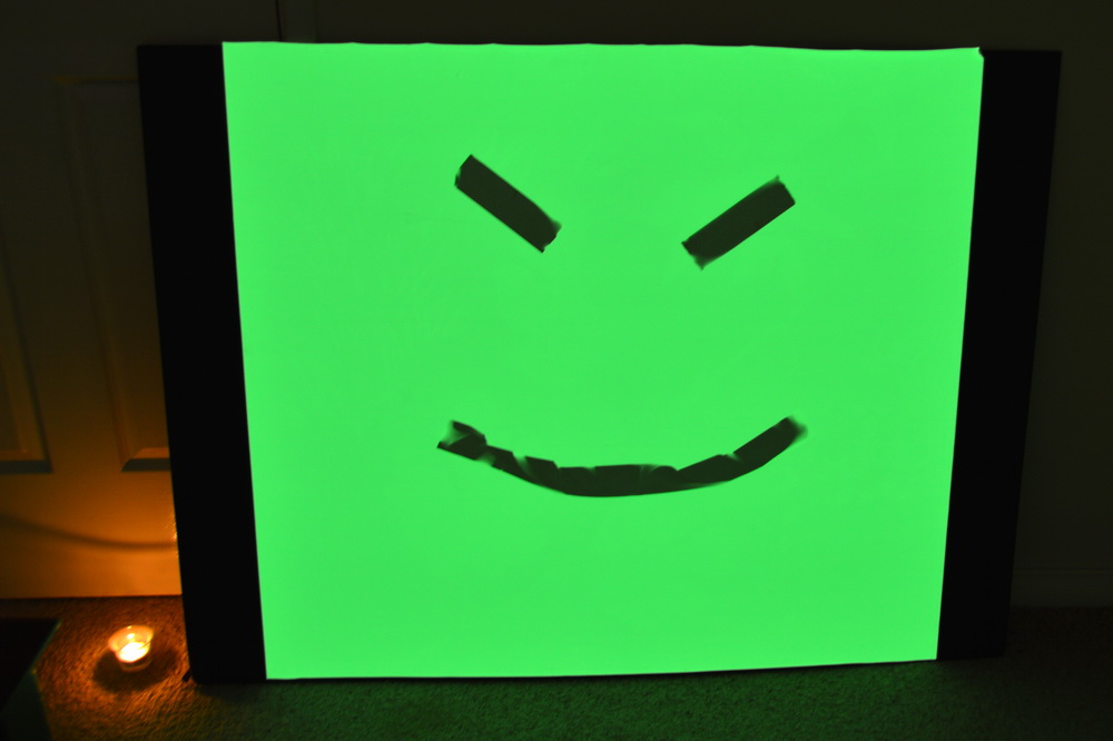 Phosphorescent sheet with smiley face after exposure to the sun with some duct tape to mask the light